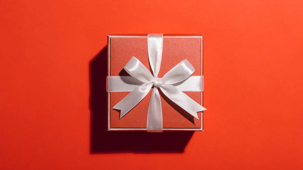 A gift box tied with a ribbon, cut out against a solid bright background.