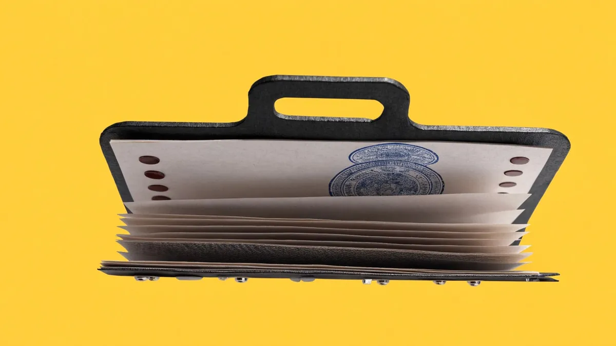 A folder stamped with an approval mark on a desk, cut out against a solid bright color.