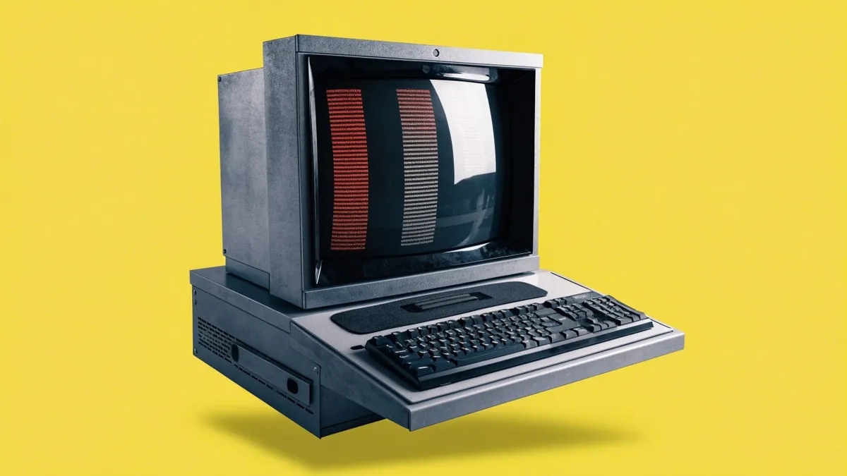 A beige desktop computer terminal with a boxy monitor and keyboard, cut out against a solid bright color.