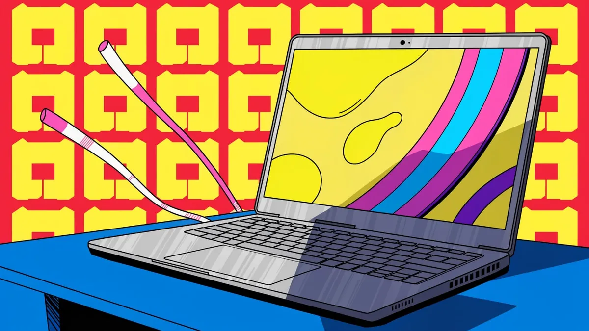 A gray laptop open on a blue desk, its screen filled with yellow and a band of pink, cyan and purple stripes, with two pink and white striped sticks angled up behind it against a red wall with a repeating yellow block pattern.