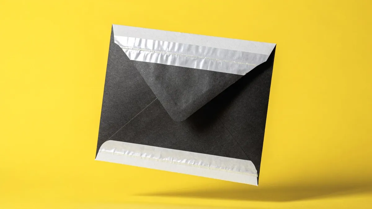 A sealed envelope on a bare desk, cut out against a solid bright color.