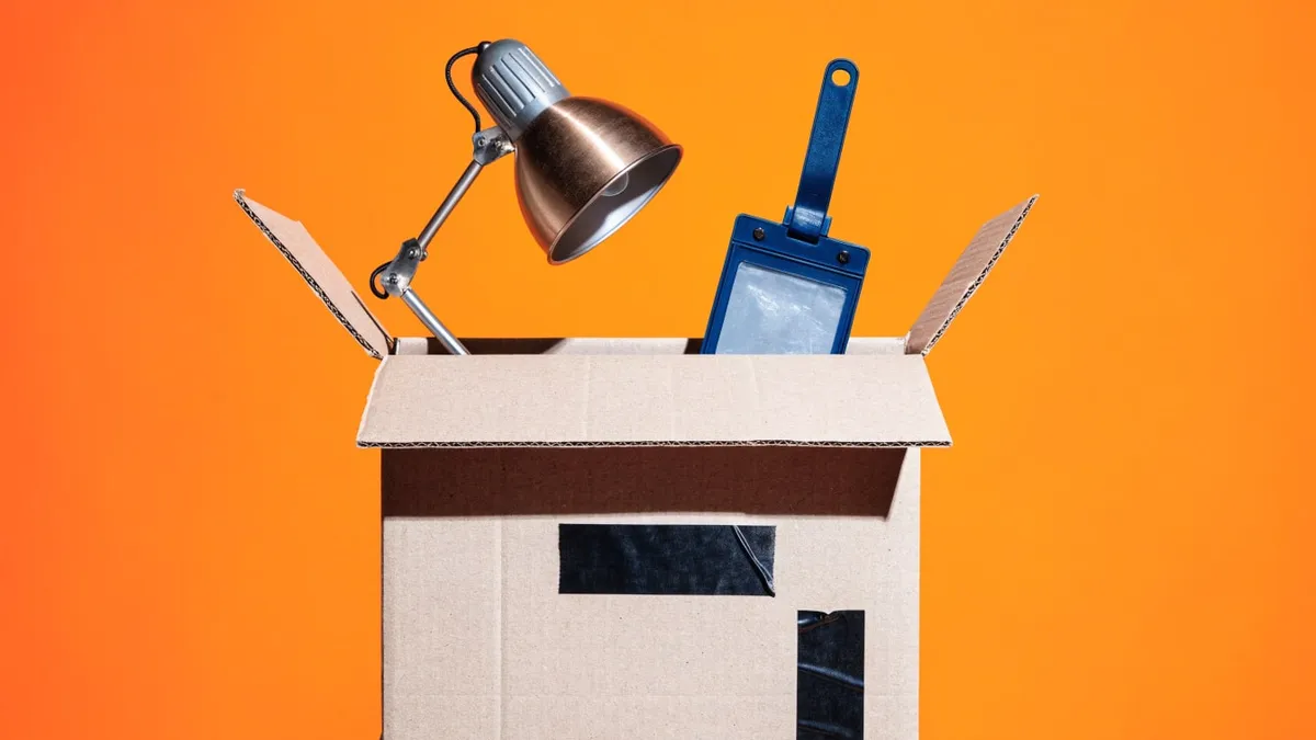 A cardboard box holding a desk lamp and a security badge, cut out against a solid bright color.